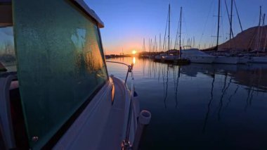 Tekne yan penceresinde çiğ taneleri marina rıhtımında güneşin doğuşunda ıslanıyor.