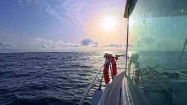 Güneşin doğuşuyla birlikte teknenin yan camı okyanus denizinde güzel güneş ışığıyla yelken açıyor.