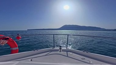 Bir yatın pruvası, açık denizde, açık denizde, berrak, güneşli bir gökyüzünün altında süzülüyor.