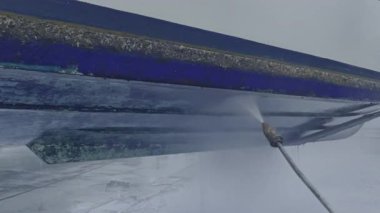 Kuru rıhtımda bakım sırasında tekne gövdesinden eski antiseptik boyayı söküp alan yüksek basınçlı su aleti.