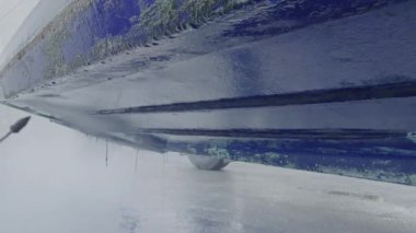 Kuru rıhtımda bakım sırasında tekne gövdesinden eski antiseptik boyayı söküp alan yüksek basınçlı su aleti.