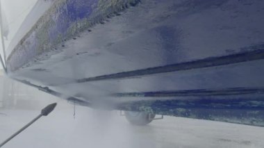 Kuru rıhtımda bakım sırasında tekne gövdesinden eski antiseptik boyayı söküp alan yüksek basınçlı su aleti.