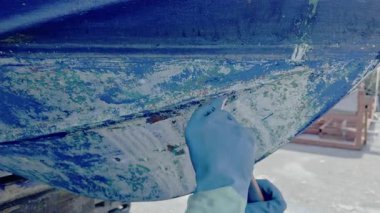 El kazıyıcı, eski anti-osmoz gövde tedavisine hazır hale getirmek için tekne gövdesinden eski antiseptik boyayı çıkarır.