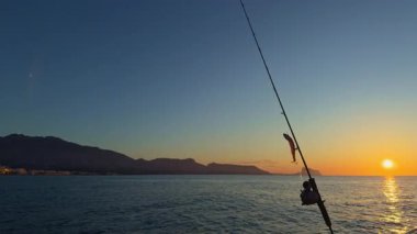 Akdeniz 'de gün doğumunda elinde olta kamışı ve makaralı bir tekneyle Altea Sunrise deniz manzarası