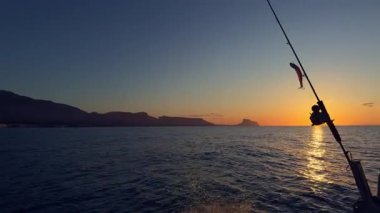 Akdeniz 'de gün doğumunda elinde olta kamışı ve makaralı bir tekneyle Altea Sunrise deniz manzarası