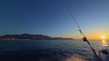 Akdeniz 'de gün doğumunda elinde olta kamışı ve makaralı bir tekneyle Altea Sunrise deniz manzarası