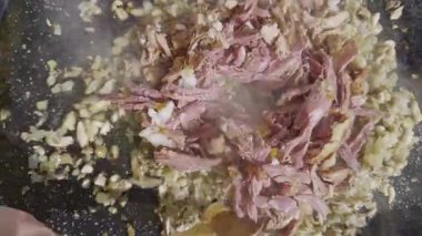 Kızarmış sotelenmiş soğan ve ördek eti tavada, ördek paella tarifi hazırlama sırasında buharda pişiyor.