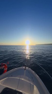 Yat yayı, yaz günbatımında sabah güneş doğarken dalgalar arasında süzülüyor.