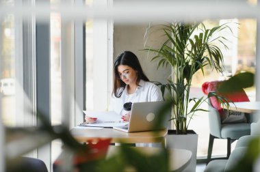 Gülümseyen kız öğrenci çalışması Skype öğretmeniyle, mutlu genç kadın dil öğreniyor. Ders dinliyor. Webinar yazıları yazıyor..