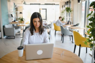 Cafe 'de internetten bilgisayar ve kulaklık kullanan neşeli bir kız öğrenci..