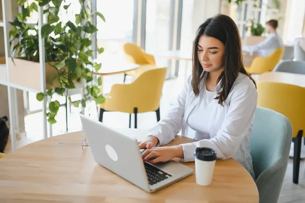 Cafe 'de internetten bilgisayar ve kulaklık kullanan neşeli bir kız öğrenci..