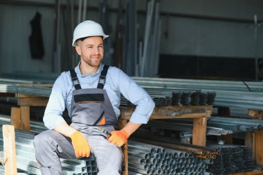Üniformalı fabrika işçisinin portresi üretim hattında endüstriyel makinenin yanında duruyor. Endüstride çalışan insanlar.