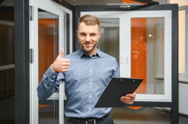 Dükkanda anahtarı olan dost canlısı bir satıcı. Ev için geniş bir pencere ve kapı seçimi. Ev yenileme konsepti.