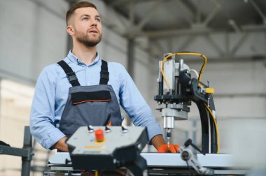 Erkek fabrika tamircileri veya güvenlik üniformalı mühendisler endüstriyel üretim hatlarında metal sondaj makineleri, çelik işleme endüstrisi ve mekanik bakım üzerinde çalışıyorlar.