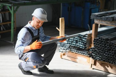 Profesyonel kumaş işçisi. Metal işleme tesisi. Metal profil deposunda çalışan bir işçi.