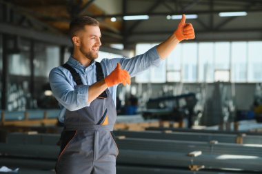 Erkek fabrika tamircileri veya güvenlik üniformalı mühendisler endüstriyel üretim hatlarında metal sondaj makineleri, çelik işleme endüstrisi ve mekanik bakım üzerinde çalışıyorlar.