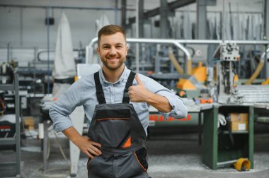 Erkek fabrika tamircileri veya güvenlik üniformalı mühendisler endüstriyel üretim hatlarında metal sondaj makineleri, çelik işleme endüstrisi ve mekanik bakım üzerinde çalışıyorlar.