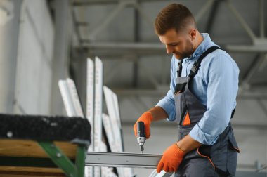 Alüminyum, PVC pencere ve kapı üretim fabrikası. PVC pencere ve kapılarını birleştiren el işçisi.