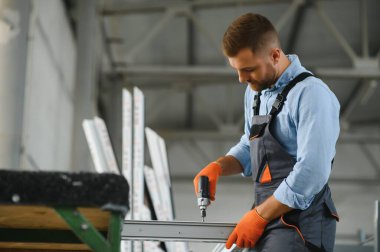 Alüminyum, PVC pencere ve kapı üretim fabrikası. PVC pencere ve kapılarını birleştiren el işçisi
