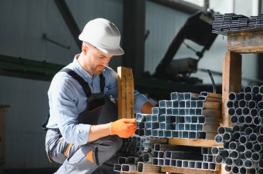Erkek fabrika tamircileri veya güvenlik üniformalı mühendisler endüstriyel üretim hatlarında metal sondaj makineleri, çelik işleme endüstrisi ve mekanik bakım üzerinde çalışıyorlar.