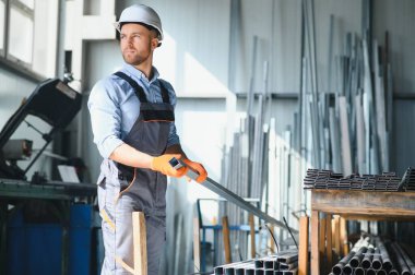 Erkek fabrika tamircileri veya güvenlik üniformalı mühendisler endüstriyel üretim hatlarında metal sondaj makineleri, çelik işleme endüstrisi ve mekanik bakım üzerinde çalışıyorlar.