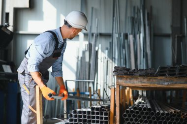 Profesyonel kumaş işçisi. Metal işleme tesisi. Metal profil deposunda çalışan bir işçi.