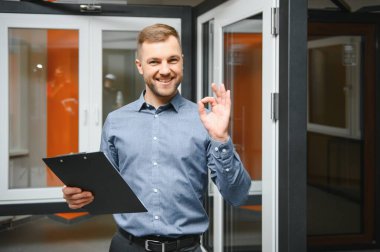 Dükkanda anahtarı olan dost canlısı bir satıcı. Ev için geniş bir pencere ve kapı seçimi. Ev yenileme konsepti.