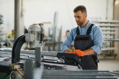 Erkek fabrika tamircileri veya güvenlik üniformalı mühendisler endüstriyel üretim hatlarında metal sondaj makineleri, çelik işleme endüstrisi ve mekanik bakım üzerinde çalışıyorlar.