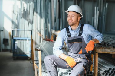 Erkek fabrika tamircileri veya güvenlik üniformalı mühendisler endüstriyel üretim hatlarında metal sondaj makineleri, çelik işleme endüstrisi ve mekanik bakım üzerinde çalışıyorlar.