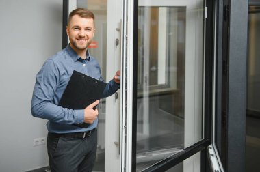 Dükkanda anahtarı olan dost canlısı bir satıcı. Ev için geniş bir pencere ve kapı seçimi. Ev yenileme konsepti.