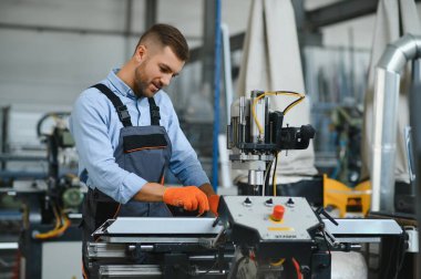 Erkek fabrika tamircileri veya güvenlik üniformalı mühendisler endüstriyel üretim hatlarında metal sondaj makineleri, çelik işleme endüstrisi ve mekanik bakım üzerinde çalışıyorlar.