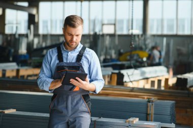 Profesyonel kumaş işçisi. Metal işleme tesisi. Metal profil deposunda çalışan bir işçi.
