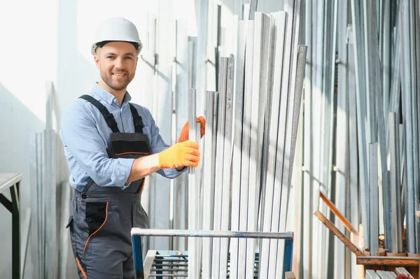 Üniformalı fabrika işçisinin portresi üretim hattında endüstriyel makinenin yanında duruyor. Endüstride çalışan insanlar.