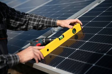 Metal yapıya güneş panelleri yerleştiren profesyonel işçiler, farklı ekipmanlar kullanıyorlar, kask takıyorlar. Enerji çözümü için yenilikçi bir çözüm. Yenilenebilir kaynakları kullan. Yeşil enerji
