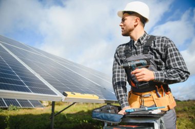 Uzman, güneş pillerinin kalitesini inceliyor. Üniformalı ve kasklı bir işçi. Ekoloji güç koruma kavramı