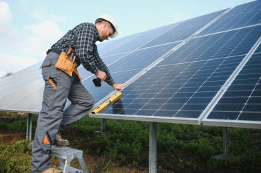 Metal yapıya güneş panelleri yerleştiren profesyonel işçiler, farklı ekipmanlar kullanıyorlar, kask takıyorlar. Enerji çözümü için yenilikçi bir çözüm. Yenilenebilir kaynakları kullan. Yeşil enerji