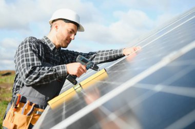 Uzman, güneş pillerinin kalitesini inceliyor. Üniformalı ve kasklı bir işçi. Ekoloji güç koruma kavramı