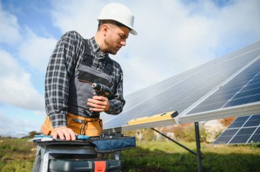 Metal yapıya güneş panelleri yerleştiren profesyonel işçiler, farklı ekipmanlar kullanıyorlar, kask takıyorlar. Enerji çözümü için yenilikçi bir çözüm. Yenilenebilir kaynakları kullan. Yeşil enerji