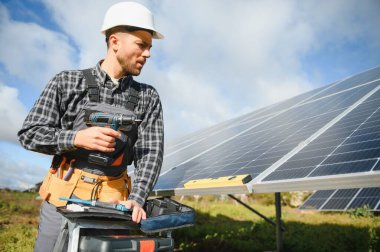 Metal yapıya güneş panelleri yerleştiren profesyonel işçiler, farklı ekipmanlar kullanıyorlar, kask takıyorlar. Enerji çözümü için yenilikçi bir çözüm. Yenilenebilir kaynakları kullan. Yeşil enerji