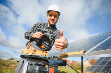 Metal yapıya güneş panelleri yerleştiren profesyonel işçiler, farklı ekipmanlar kullanıyorlar, kask takıyorlar. Enerji çözümü için yenilikçi bir çözüm. Yenilenebilir kaynakları kullan. Yeşil enerji