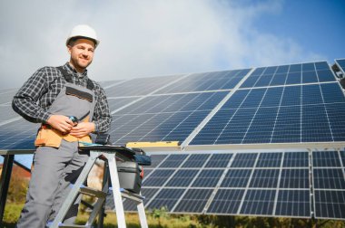 Güneş enerjisi santrali işçisi panellerin durumunu kontrol ediyor.