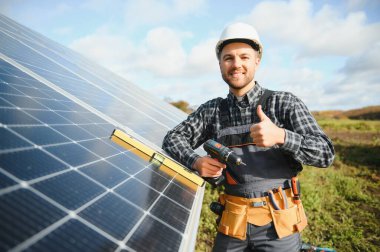 Güneş enerjisi santrali işçisi panellerin durumunu kontrol ediyor.