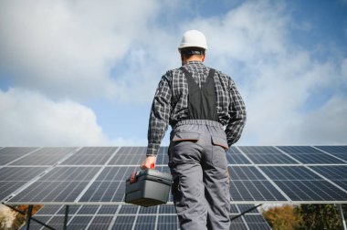 Güneş enerjisi santrali işçisi panellerin durumunu kontrol ediyor.
