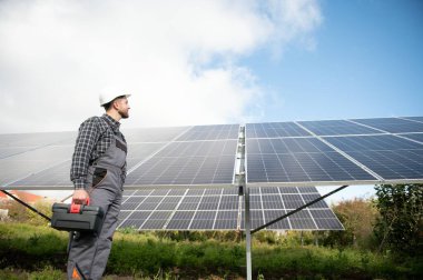 Metal yapıya güneş panelleri yerleştiren profesyonel işçiler, farklı ekipmanlar kullanıyorlar, kask takıyorlar. Enerji çözümü için yenilikçi bir çözüm. Yenilenebilir kaynakları kullan. Yeşil enerji