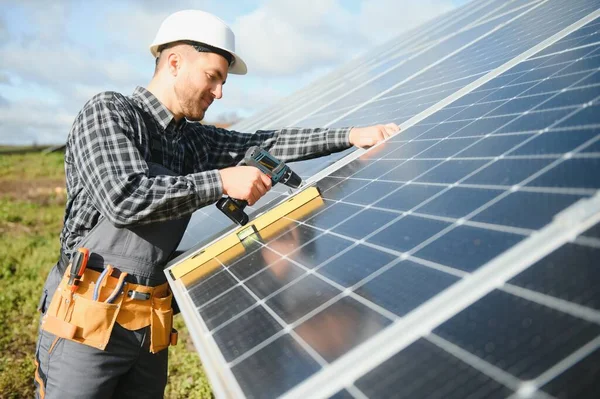 stock image Professional worker installing solar panels on the metal construction, using different equipment, wearing helmet. Innovative solution for energy solving. Use renewable resources. Green energy