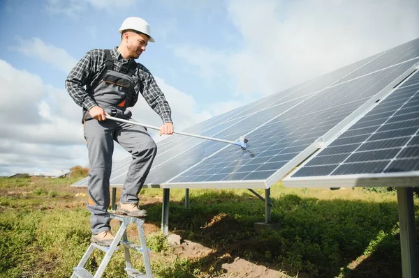 A worker cleaning dust and dirt form solar panels