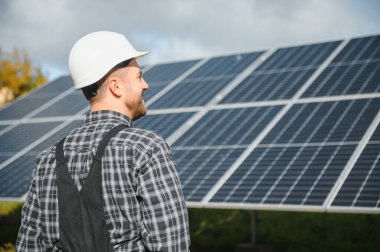 Güneş enerjisi santrali işçisi panellerin durumunu kontrol ediyor.