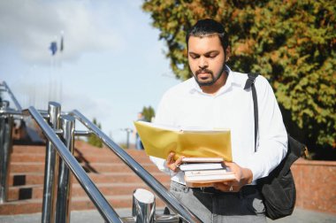 Okula dönelim. Mutlu Hintli ya da Arap erkek öğrenci, şık giyinmiş.