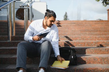 Hintli genç öğrenci kitap taşıyor.