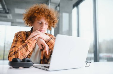 Yeni bir başlangıç projesi üzerinde çalışan şık bir erkek serbest yazar, internet araştırmacılarını dizüstü bilgisayar ve şehir kafesindeki 4G internete kablosuz bağlantı kullanarak veri analizi yaptırıyor..